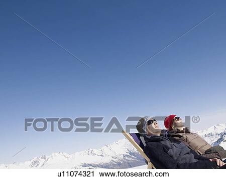 Stock Image - man and woman on deck chair up mountain. Fotosearch