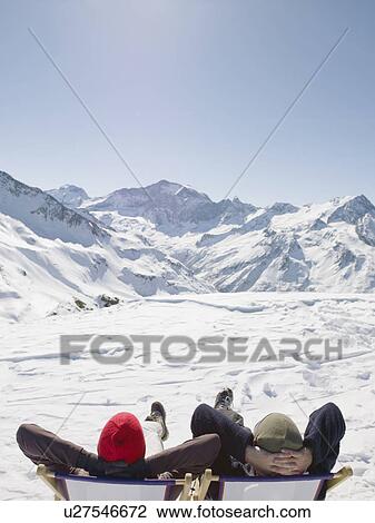 Stock Image - man and woman on deck chair up mountain. Fotosearch