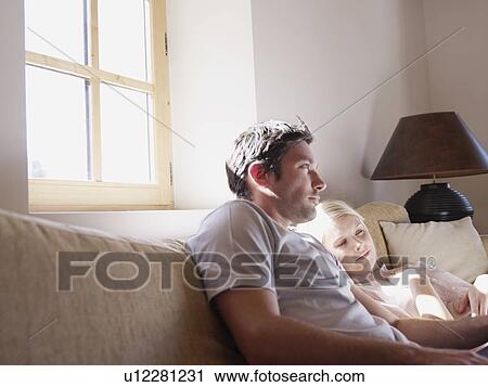 Stock Image - man and woman on sofa in living room. Fotosearch