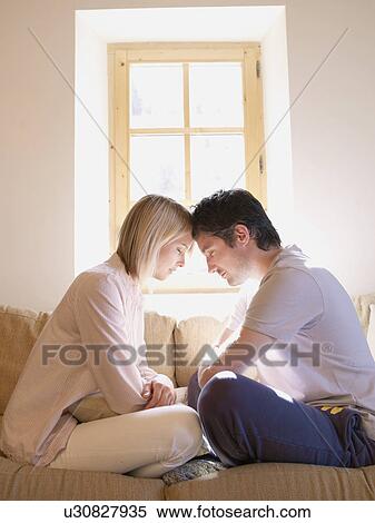 Stock Photography - man and woman on sofa in living room. Fotosearch