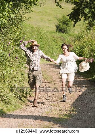 Stock Image - Man and woman running down country lane. Fotosearch