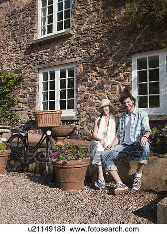 Stock Photo - Man and woman sit outside country house. Fotosearch