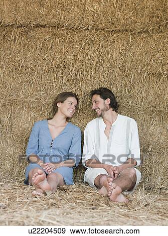 Man and woman sitting against hay bale View Large Photo Image Stock Photo - Man and woman sitting against hay bale. Fotosearch