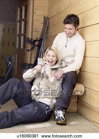 Stock Image - man and woman sitting outside chalet. Fotosearch