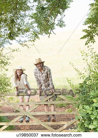Stock Photo - Man and woman standing on country gate. Fotosearch