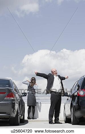 Stock Image - man and woman stretching between cars. Fotosearch