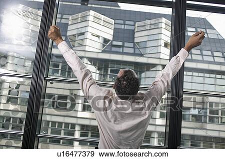 Stock Photo - man at window with raised arms. Fotosearch