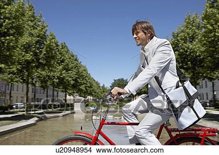 Picture - Man bicycling with bag across the city. Fotosearch