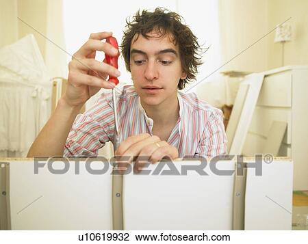 Stock Image - Man building furniture. Fotosearch