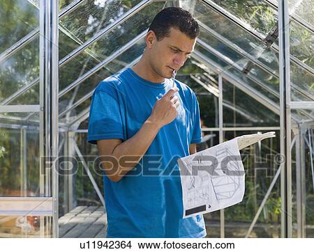 Picture - Man building greenhouse in garden. Fotosearch