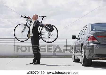 man carrying bycicle stretching near car View Large Photo Image Stock Image - man carrying bycicle stretching near car. Fotosearch