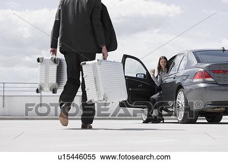 Stock Photography - man carrying cases woman waiting in car. Fotosearch