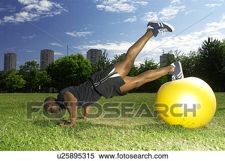 Stock Photography - man doing press ups on gym ball. Fotosearch