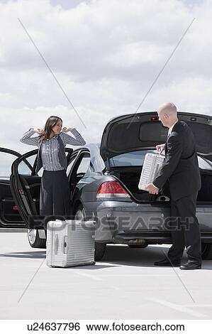 man getting case in car woman waiting View Large Photo Image Stock Photograph - man getting case in car woman waiting. Fotosearch