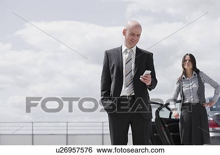 Stock Photograph - man glancing at phone woman waiting. Fotosearch