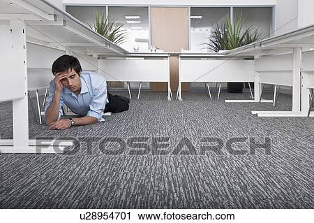 Stock Image - man hiding under desk. Fotosearch