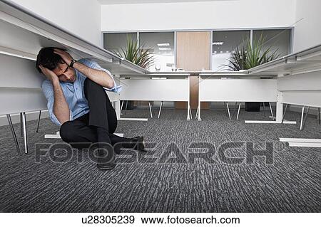 Stock Photo - man hiding under desk. Fotosearch