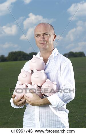 man holding piggy banks View Large Photo Image Stock Image - man holding piggy banks. Fotosearch