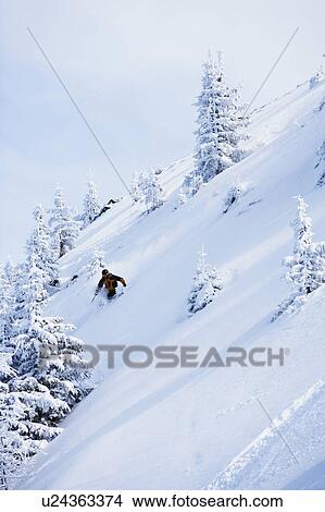 Picture - Man in black & orange outfit off-piste.. Fotosearch
