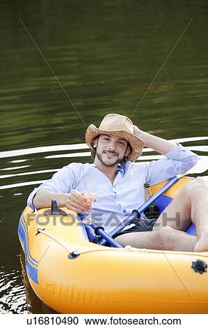 Stock Image - Man in dinghy on a country lake. Fotosearch