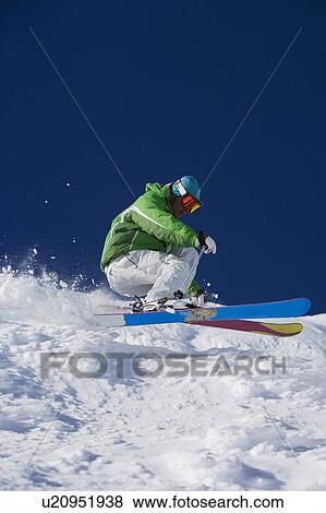 Stock Photo - Man in green carving downhill.. Fotosearch