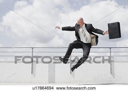 Picture - man jumping in the air with briefcase. Fotosearch
