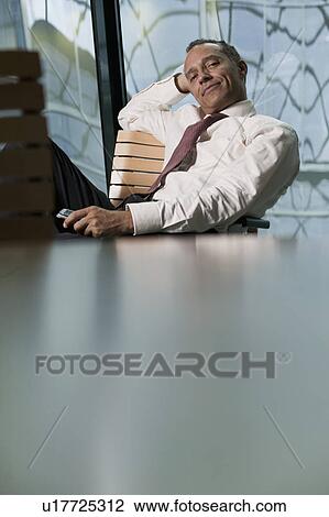 Stock Image - man leaning back in chair smiling. Fotosearch