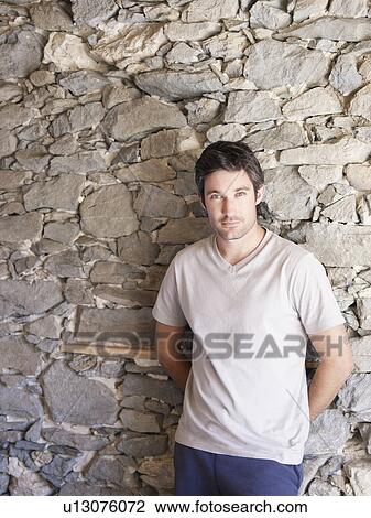 Stock Image - man leaning on rock wall in chalet. Fotosearch