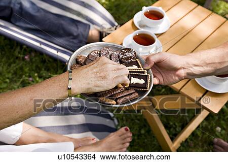 Picture - man offering biscuits to senior woman. Fotosearch