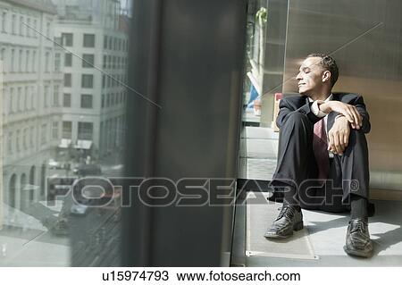 Stock Image - man on floor looking out a window. Fotosearch