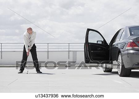 Stock Photograph - man playing golf near car. Fotosearch
