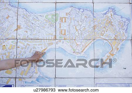 Stock Image - Man pointing with finger on tiled map. Fotosearch