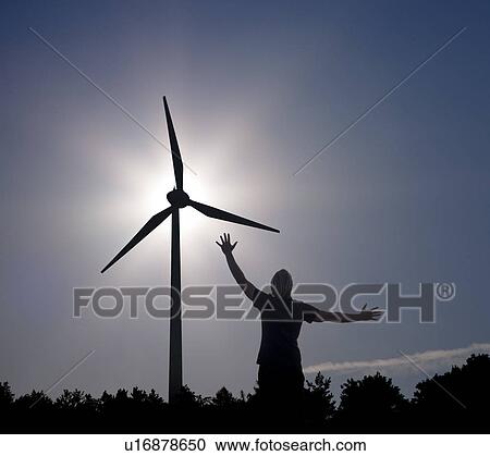 Stock Image - man raising arms at sun and Wind Turbine. Fotosearch