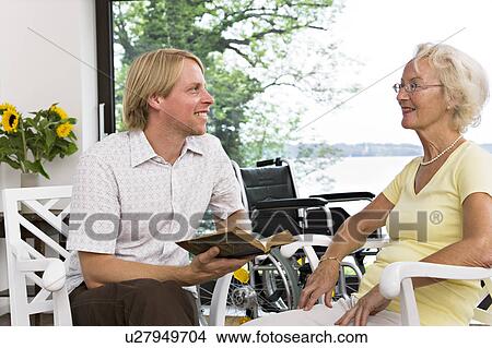man reading book to senior woman View Large Photo Image Picture - man reading book to senior woman. Fotosearch