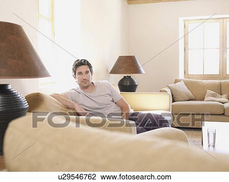 Man relaxing on sofa in living room View Large Photo Image Stock Image - Man relaxing on sofa in living room. Fotosearch