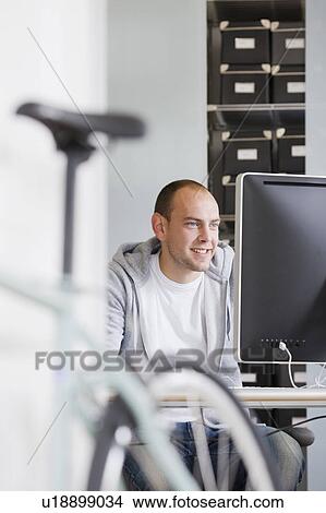 Picture - man sitting at desk working. Fotosearch