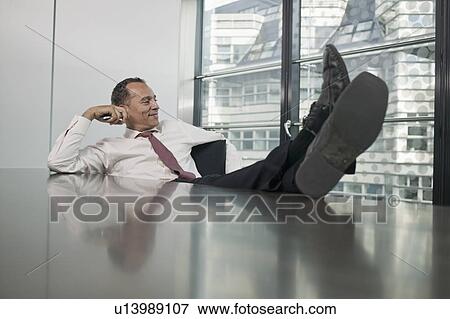 Stock Photo - man sitting at table feet up. Fotosearch