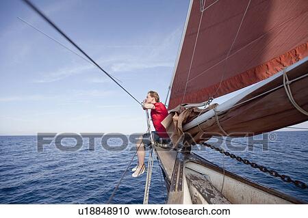 Stock Image - Man sitting at the bow of a ship. Fotosearch