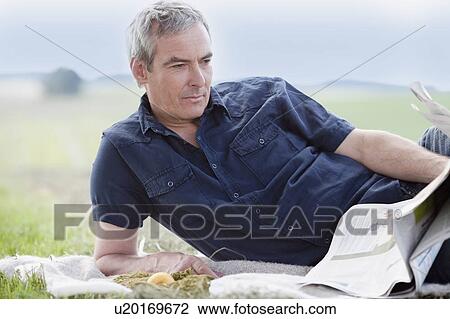 man sitting on grass reading newspaper View Large Photo Image Stock Image - man sitting on grass reading newspaper. Fotosearch