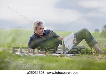 man sitting on grass reading newspaper View Large Photo Image Stock Image - man sitting on grass reading newspaper. Fotosearch