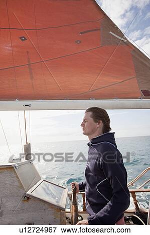 Man standing at wooden steering wheel View Large Photo Image Stock Photo - Man standing at wooden steering wheel. Fotosearch