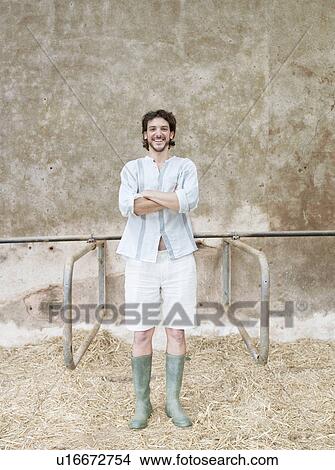 Picture - Man standing in cattle shed. Fotosearch