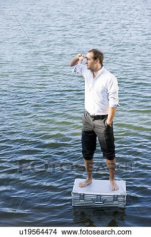 Picture - man standing on floating suitcase. Fotosearch