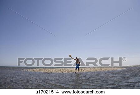 Picture - Man standing on small island. Fotosearch
