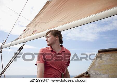 Stock Photo - Man standing under a sail. Fotosearch