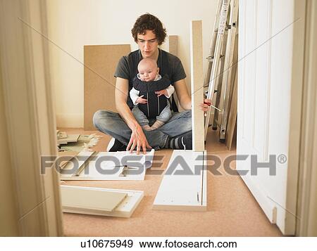 Stock Photo - Man with baby building furniture. Fotosearch