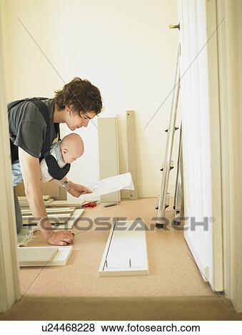 Stock Photo - Man with baby building furniture. Fotosearch