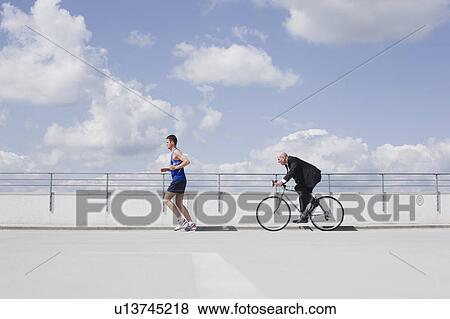man with bycicle chasing jogger View Large Photo Image Stock Photo - man with bycicle chasing jogger. Fotosearch