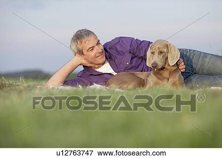 man with dog lying on the grass smiling View Large Photo Image Stock Photo - man with dog lying on the grass smiling. Fotosearch