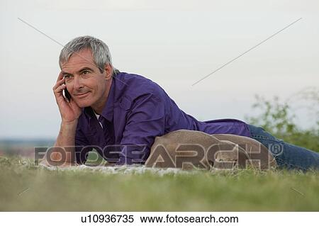 Stock Photography - man with dog on the phone in the grass. Fotosearch